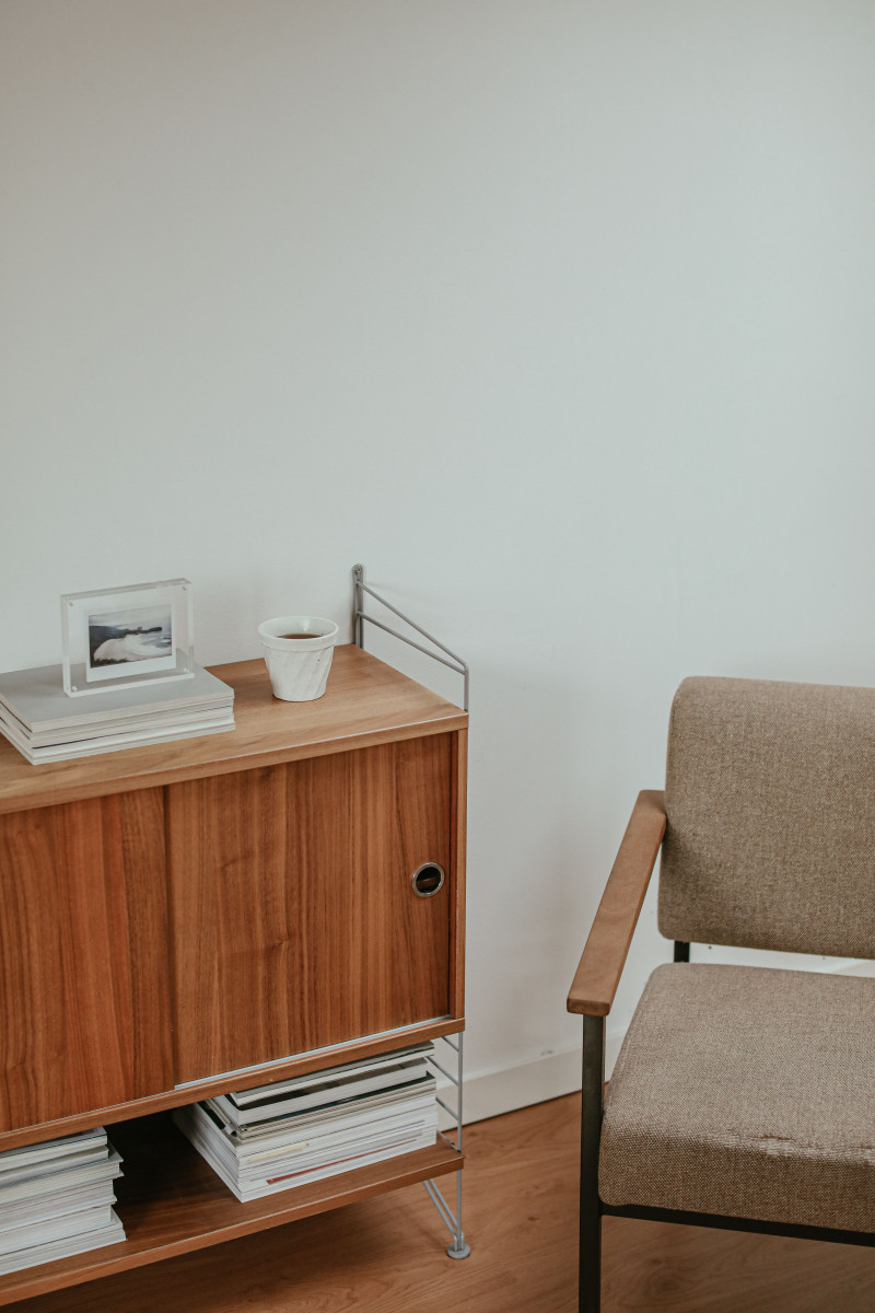 A walnut cabinet and a small armchair in a corner.